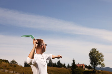 Man throwing boomerang outdoors on sunny day. Space for text