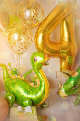 Room decorated for a birthday party with golden, green and yellow baloons, large inflatable number...