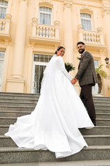 Fototapeta premium Young bride and groom on stairs outdoors, low angle view. Wedding couple