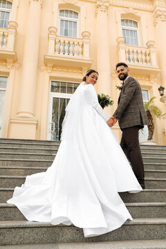 Young Bride And Groom On Stairs Outdoors, Low Angle View. Wedding Couple