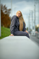 Fototapeta premium A young girl in a tracksuit stands in a city park