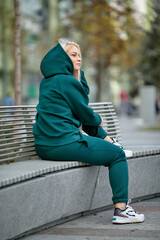 A young girl in a tracksuit stands in a city park