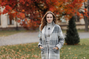 Portrait of young smiling girl in a gray coat at autumn park