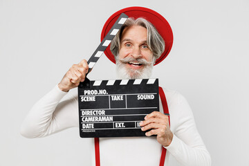 Elderly gray-haired mustache bearded man 50s in turtleneck red hat suspenders holding classic black film make clapperboard isolated on plain white background studio portrait People lifestyle concept