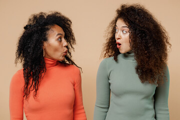 Two shocked amazed astonished young curly black women friends 20s wearing casual shirts clothes...