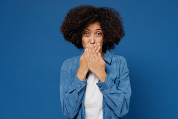 Young shocked astonished impressed upset black woman 20s in casual clothes shirt white t-shirt cover mouth with hand isolated on plain dark blue background studio portrait. People lifestyle concept.