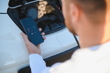 Man charges an electric car at the charging station