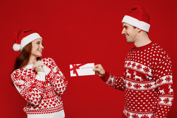 Young amazed couple friends two man woman in sweater hat give gift certificate coupon voucher card...