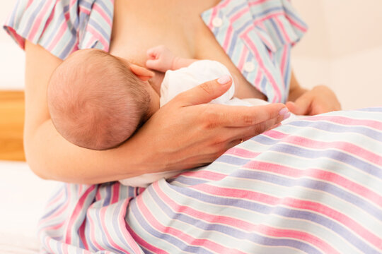 The mom is breastfeeding her newborn baby on the bed