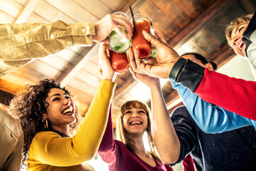 Multi ethnic friends group toasting cocktails - Happy young people having fun celebrating indoor...