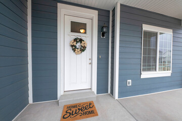 Front entrance exterior with gray vinyl wood siding and concrete flooring