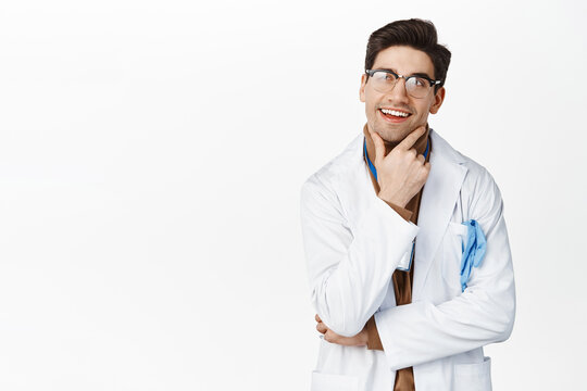 Image of thinking doctor with pleased smiling face, looking up thoughtful, standing over white background