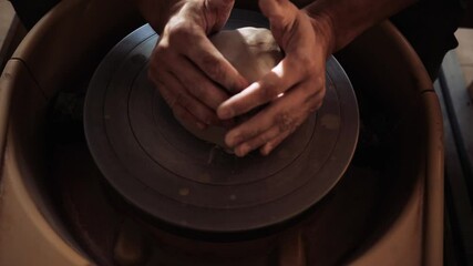 A man moistens a potter's wheel with water and throws a lump of clay on it. The beginning of the potter's work on the potter's wheel. High quality 4k footage