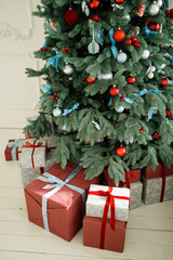Many beautiful gift boxes under Christmas tree, vertical photo. Christmas tree with gifts in red and blue colors