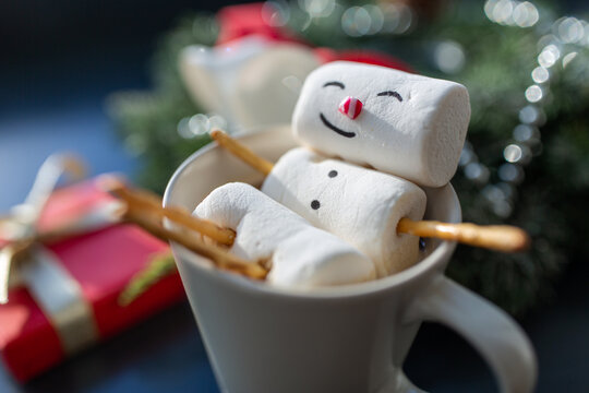 christmas, winter holidays and leisure concept - close up of marshmallow snowman taking bath in cup of coffee