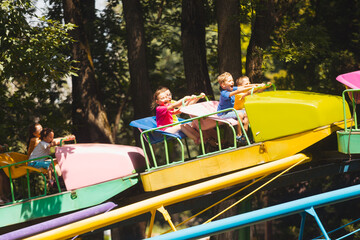 The happy kids on a roller coaster in the amusement park