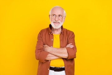 Photo of dreamy inspired grandpa crossed hands look empty space wear specs brown shirt isolated yellow color background