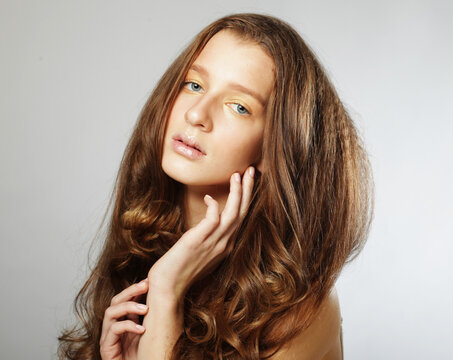 Close up picture of young woman with long and shiny wavy hair.