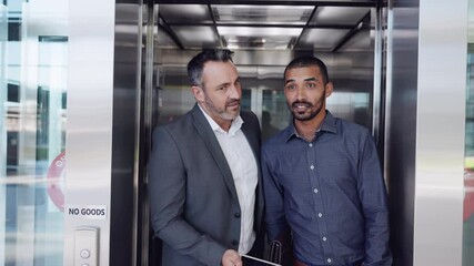 Two businessmen talking while walking out of an elevator