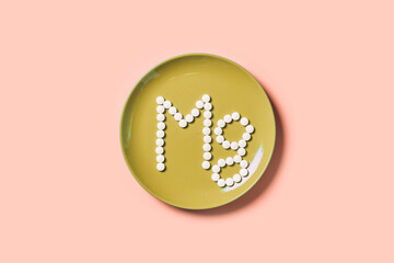 Pills with mineral Mg or magnesium on yellow plate. Mg inscription made of medical pills