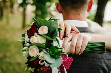 The bride and groom with a wedding bouquet, hugging and standing on wedding ceremony of the outdoor...