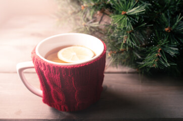 Obraz na płótnie Canvas Knitted woolen mug with warm tea and lemon in the sunlight.