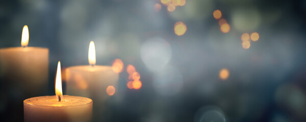 closeup of 3 burning candles on abstract black background, contemplate celebration mood with blurry lights, festive concept with copy space - obrazy, fototapety, plakaty