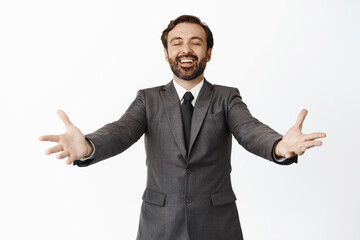Happy smiling corporate man stretching out hands, inviting clients, greeting customer in company, standing in grey suit over white background