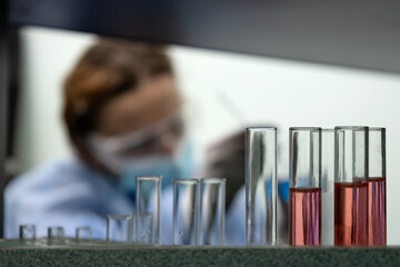 Closeup of glass tubes at the laboratory and woman scientist silhouette on the background