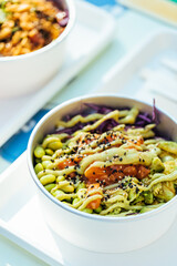 Poke bowl with salmon or tuna, avocado, beans and lot of different ingredients ready for take out