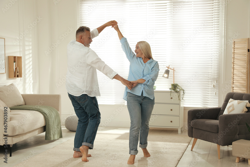 Wall mural Happy senior couple dancing together in living room