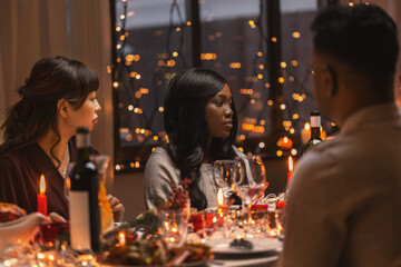 holidays, party and celebration concept - multiethnic group of happy friends having christmas dinner at home
