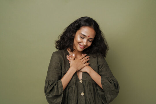 Young South Asian Woman With Bindi Smiling While Holding Hands On Her Chest