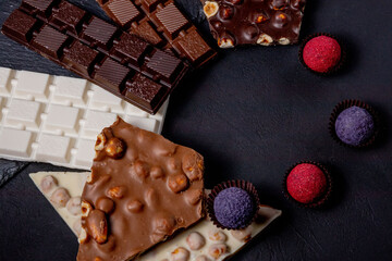 Chocolate bar, crushed pieces of dark chocolate and nuts. Praline Chocolate sweets. Copy space