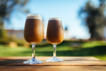 Ice coffee in two glasses in a park, for chilling and refreshment on a perfect sunny day