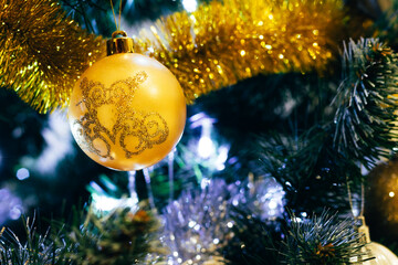 Obraz na płótnie Canvas Golden ball on decorated Christmas tree. Selective focus. Holiday card with decorations for the New Year's Eve