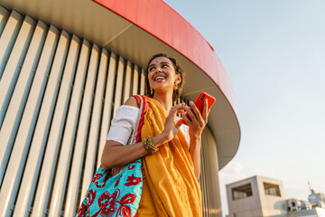 Young indian woman wearing sari using mobile phone outdoors