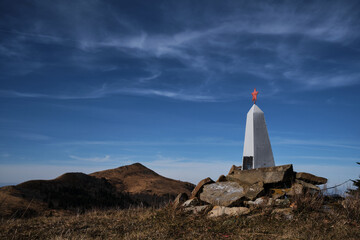 Red star on memorial symbolizes memory and sorrow. Monument to fallen soldiers in war stands on top of mountain. Journey to places of military glory of Second World War.
