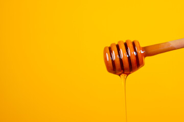 Dripping honey from spoon against yellow background