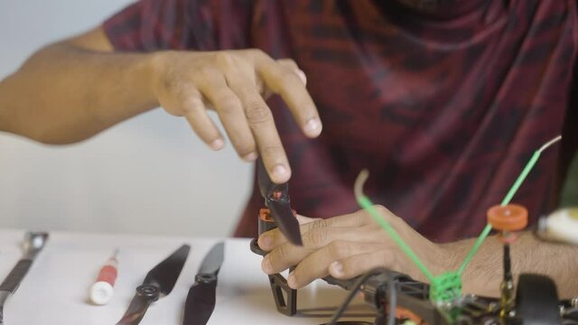 Close-up shot of Hands installing propellers to Drone by using spanner - concept of drone or quadcopter assembling and repair services.