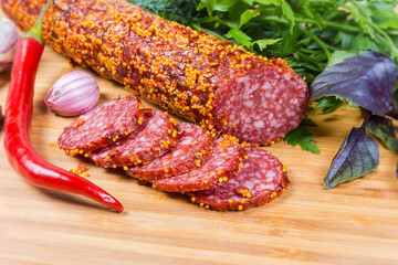 Partly sliced salami covered with French mustard close-up