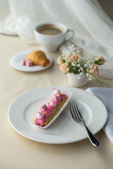 French desserts eclairs with pink icing and cup of coffee on the table