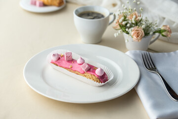 French desserts eclairs with pink icing and cup of coffee on the table