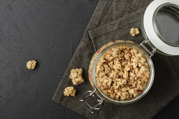 Granola in jar on dark napkin.