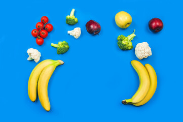 Vegetables and fruits for baby food on blue background close-up. Bananas, apples, broccoli, cauliflower, tomatoes and copy space...