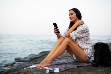 Hot woman relaxing on the sandy beach. Beautiful woman with headphones listening the music..