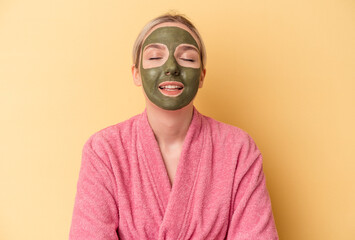 Young caucasian woman wearing face mask isolated on yellow background laughing and having fun.