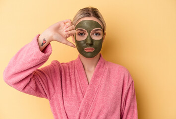 Young caucasian woman wearing face mask isolated on yellow background showing a dislike gesture,...