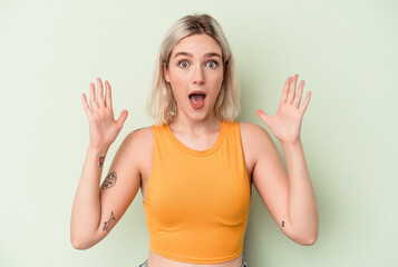 Fototapeta premium Young caucasian woman isolated on green background celebrating a victory or success, he is surprised and shocked.