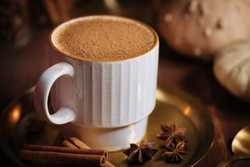 A cup of pumpkin spice latte or salep in a rustic wooden autumn atmosphere